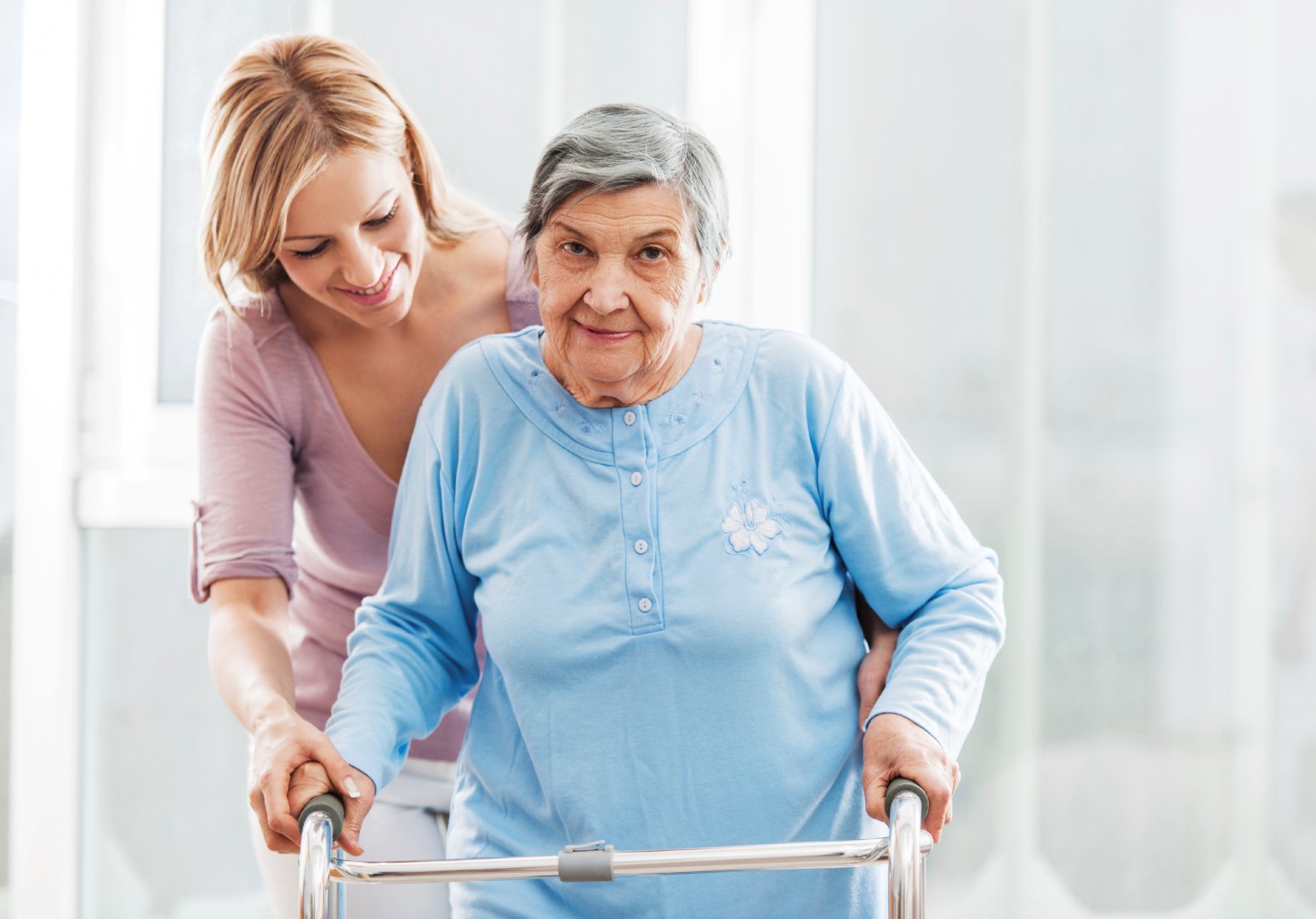 Elderly lady being helped with zimmer frame