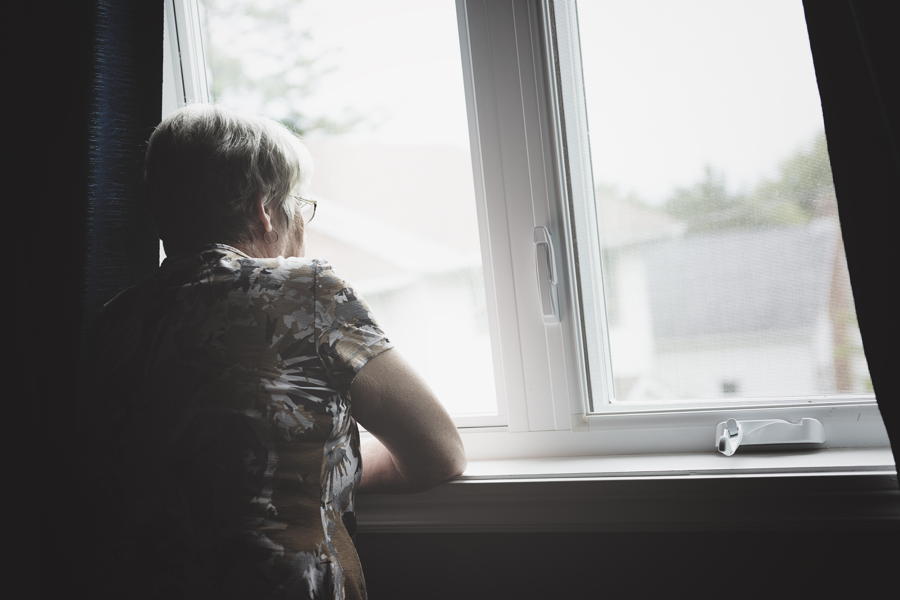 PIC - Sad older woman looking out of window