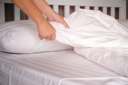 close-up of hands changing bed sheets